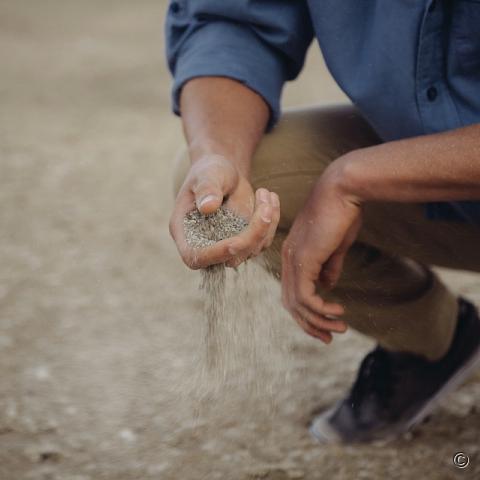 Man laat op strand zand door zijn vingers lopen